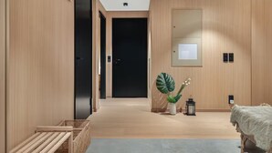 A modern hallway with wooden walls, a black door at the end, and a small plant by the door. - Stunning Lofoten Lodge with Views & Jacuzzi (Kleppstad)