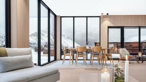 A modern interior with a sofa, dining table, and chairs, large windows with a snowy view. - Stunning Lofoten Lodge with Views & Jacuzzi (Kleppstad)
