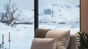 A modern living room with a large window offering a snowy mountain view. - Stunning Lofoten Lodge with Views & Jacuzzi (Kleppstad)