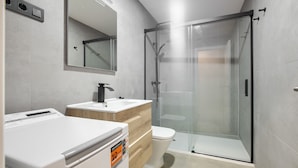 A modern bathroom with a glass-enclosed shower, a white sink, and a toilet. - Dobo Madrid Justicia (Madrid)
