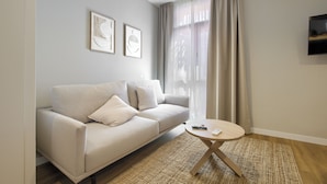 A modern living room with a beige sofa, a round coffee table, and a large window with sheer curtains. - Dobo Madrid Justicia (Madrid)