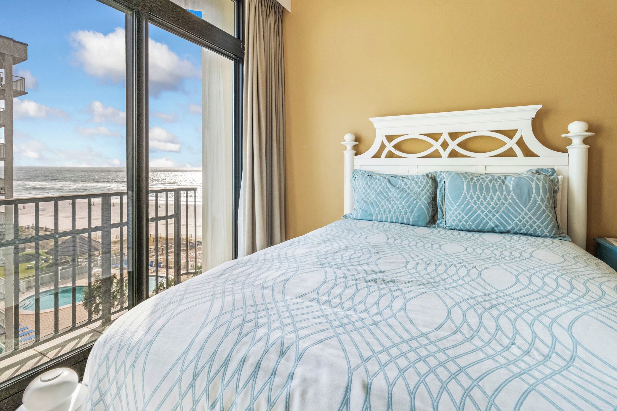 A bedroom with a large bed, a view of the beach, and a balcony.