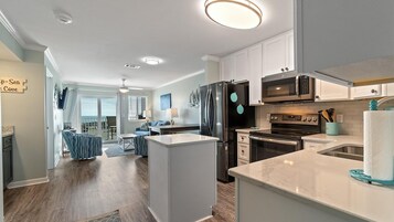 A modern kitchen with a central island, built-in appliances, and a view to the outside.
