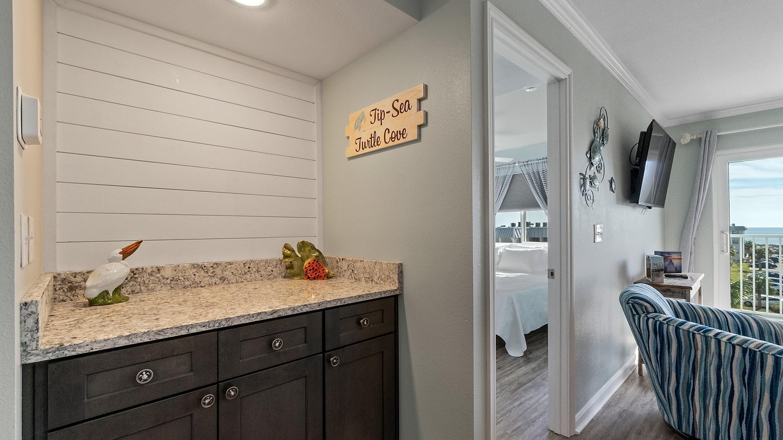 A kitchen with dark cabinets, a granite countertop, and a sign reading "Tip-SEA Turtle Cove".