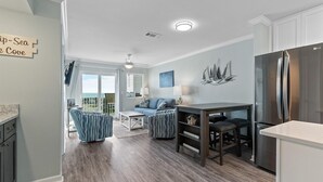 Eine moderne Küche mit einem Edelstahl-Kühlschrank, einem Esstisch mit Stühlen und einer Wohnbereich mit Sofa und Couchtisch.