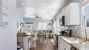 A modern kitchen with white cabinets, granite countertops, and a built-in oven. - Poseidon Palace by Southern Vacation Rentals (Gulf Shores)