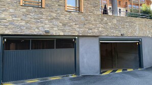 A building with a stone facade, two garage doors, and a balcony. - Brand new apartment in Briançon, cable car access (Briançon)