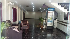 A lobby with a seating area, a Pepsi refrigerator, and a staircase. - Hotel Regal Heights (Deoghar)