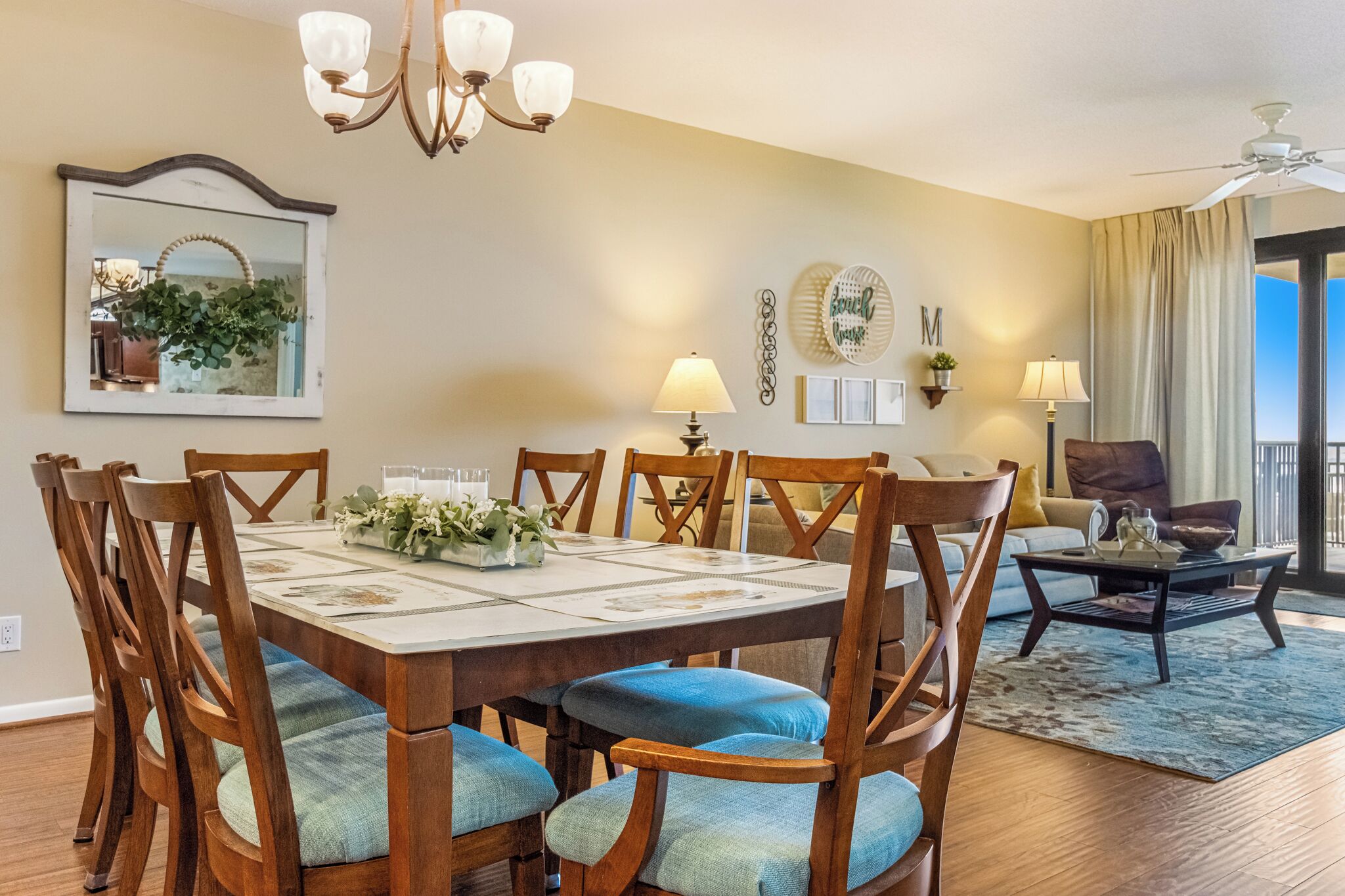 A dining area with a wooden table, blue cushioned chairs, and a chandelier.
