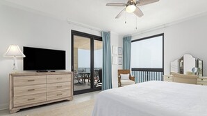 Camera d'albergo moderna con un letto grande, una TV a schermo piatto, una cassettiera in legno, un balcone con un set da pranzo e una ventola a soffitto.
