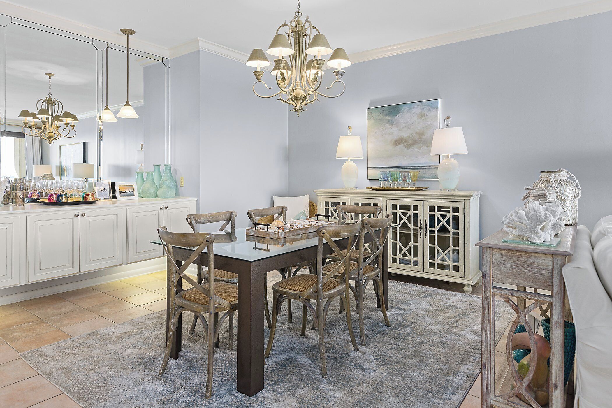A dining area with a wooden table and chairs, a chandelier, and a cabinet with decorative items.