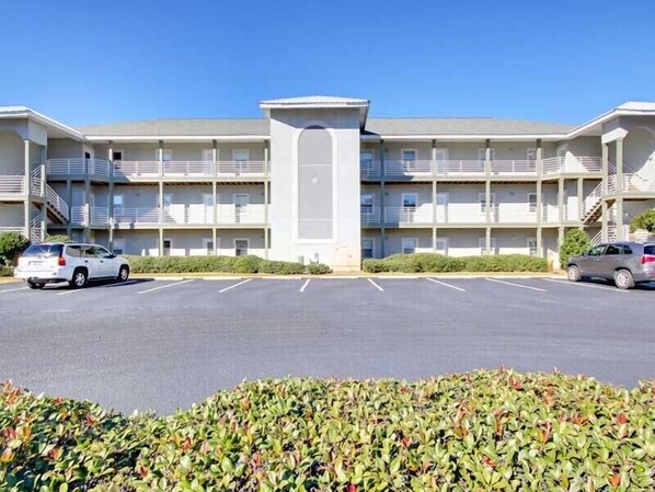 A multi-story motel with a central entrance, parking lot, and a row of balconies.