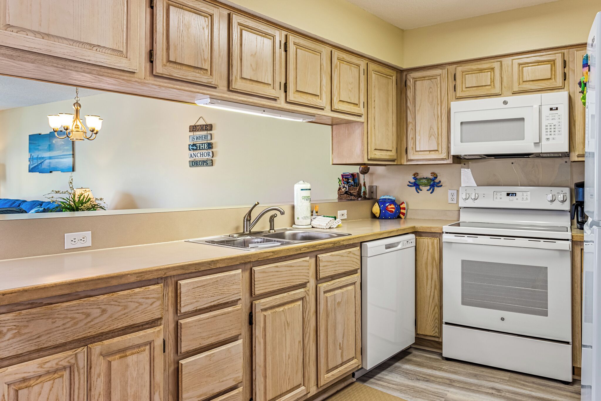 A kitchen with wooden cabinets, a microwave, an oven, and a sink.