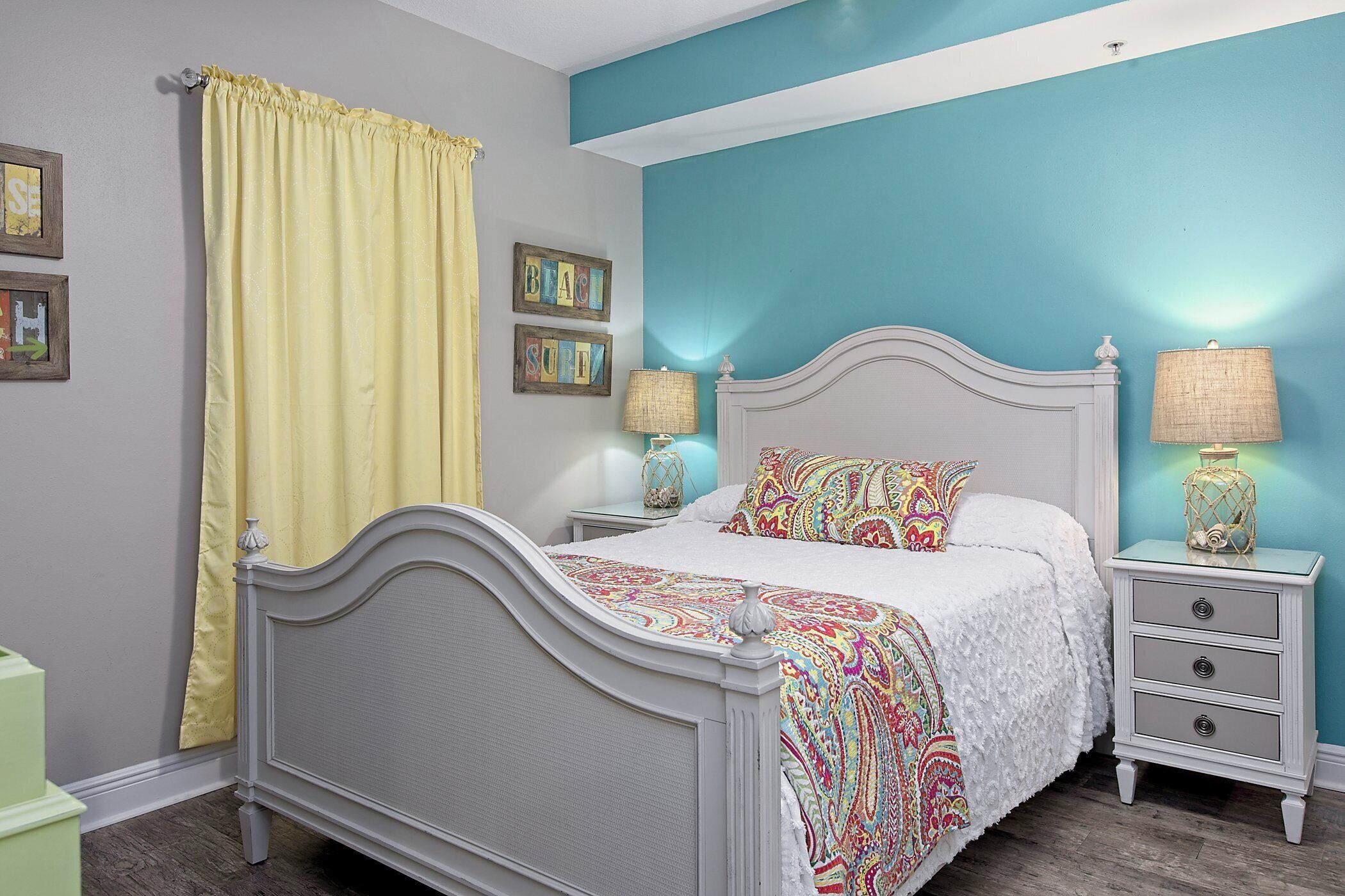 A bedroom with a bed, nightstands, and a window with curtains.