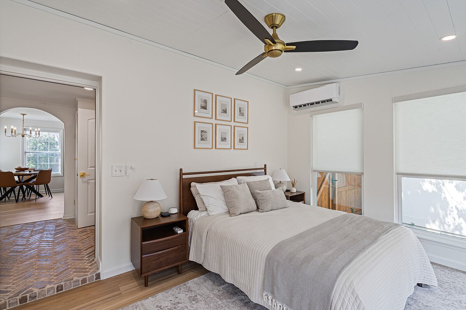 A bedroom with a bed, bedside tables, a ceiling fan, and framed pictures on the wall.