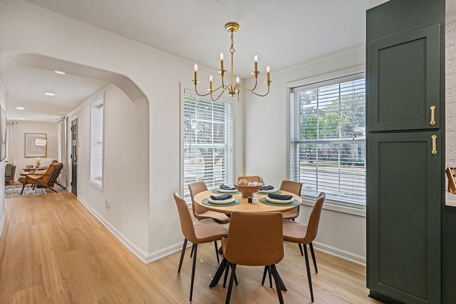 A dining area with a round table, chairs, and a chandelier.