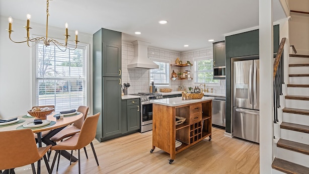 A modern kitchen with a central island, stainless steel appliances, and a dining area with a table and chairs.