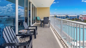 Un balcón con vista a la piscina, con sillas y una mesa.