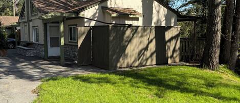 A single-story house with a stone foundation, a sloped roof, and a fenced yard.