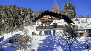 A two-story chalet with a balcony, surrounded by snow-covered trees and a clear blue sky. - Panorama Suite Waldhaus 3-bedroom apartment near Obereggen directly hiking trail (Nova Ponente)