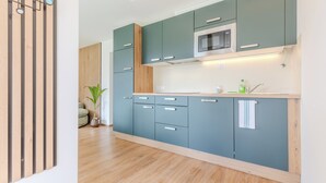 A modern kitchen with teal cabinets, a wooden countertop, and a built-in microwave. - Panorama Suite Waldhaus 3-bedroom apartment near Obereggen directly hiking trail (Nova Ponente)