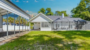 A house with a covered patio, a screened outdoor area, and a lawn. - Southern Charm by Southern Vacation Rentals (Foley)