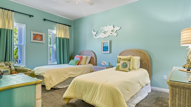 A bedroom with two beds, a seahorse wall decoration, and a beach-themed pillow. - Southern Charm by Southern Vacation Rentals (Foley)