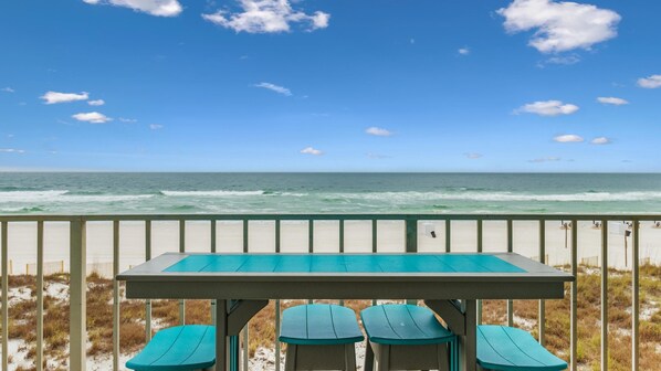 Une table située au bord de la plage, avec quatre chaises, d’où l’on a une vue sur l’océan.