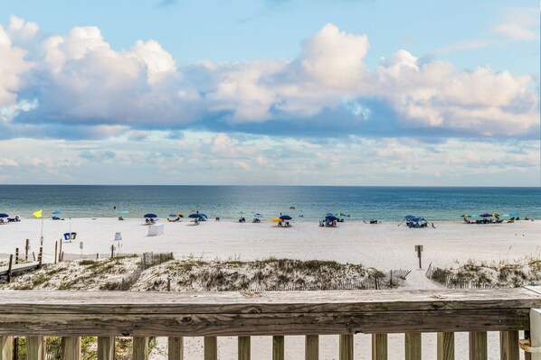A beach with a wooden boardwalk, umbrellas, and beach chairs. - Sunrise Village #210 by Southern Vacation Rentals (Gulf Shores)