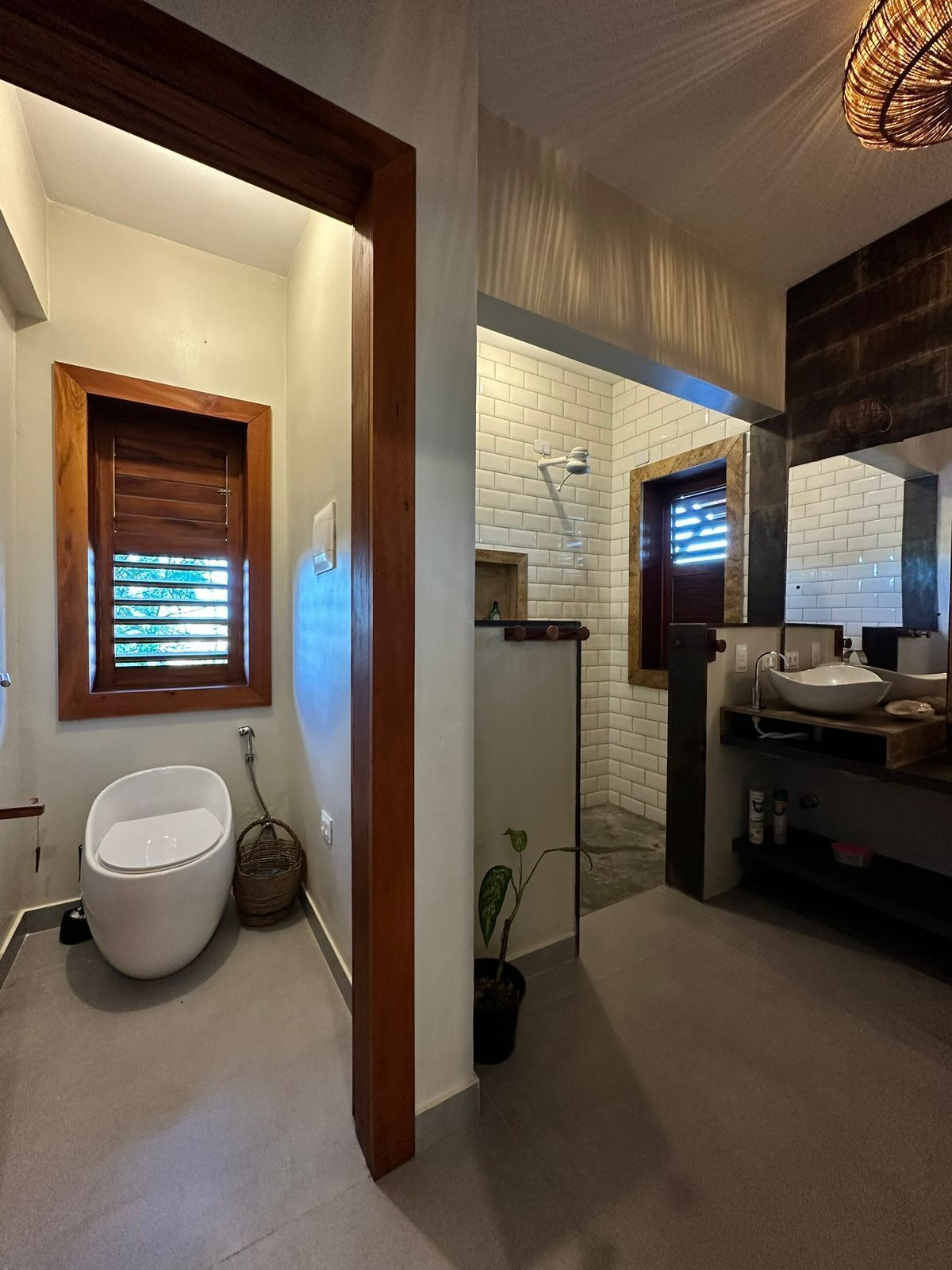 Un baño con inodoro, lavamanos y ventana con persianas.