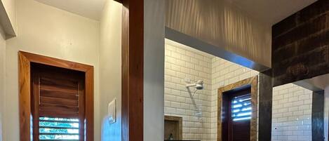 Un baño con inodoro, lavamanos y ventana con persianas.