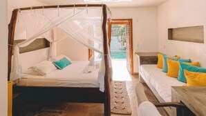 Une chambre à coucher avec un lit à baldaquin, un canapé avec des coussins, un téléviseur à écran plat et une vue sur l’extérieur.
