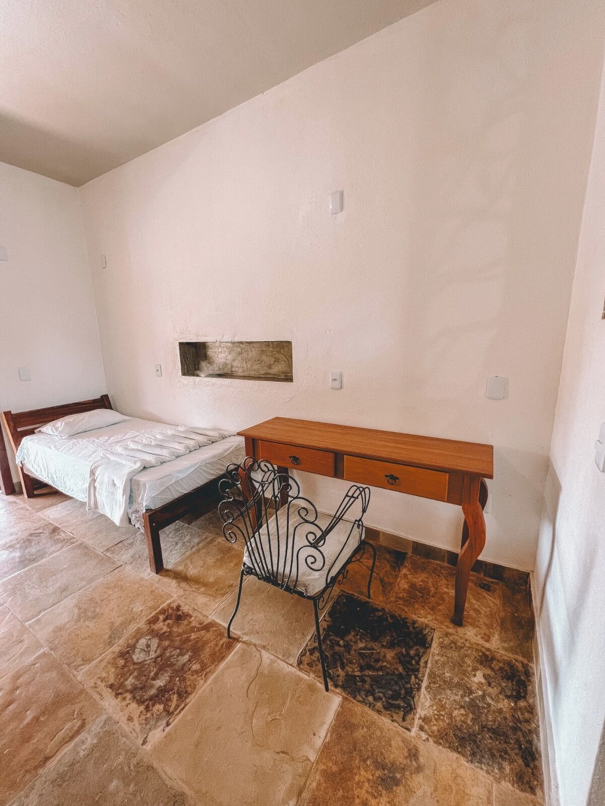 Un dormitorio con cama, un escritorio de madera y una silla.