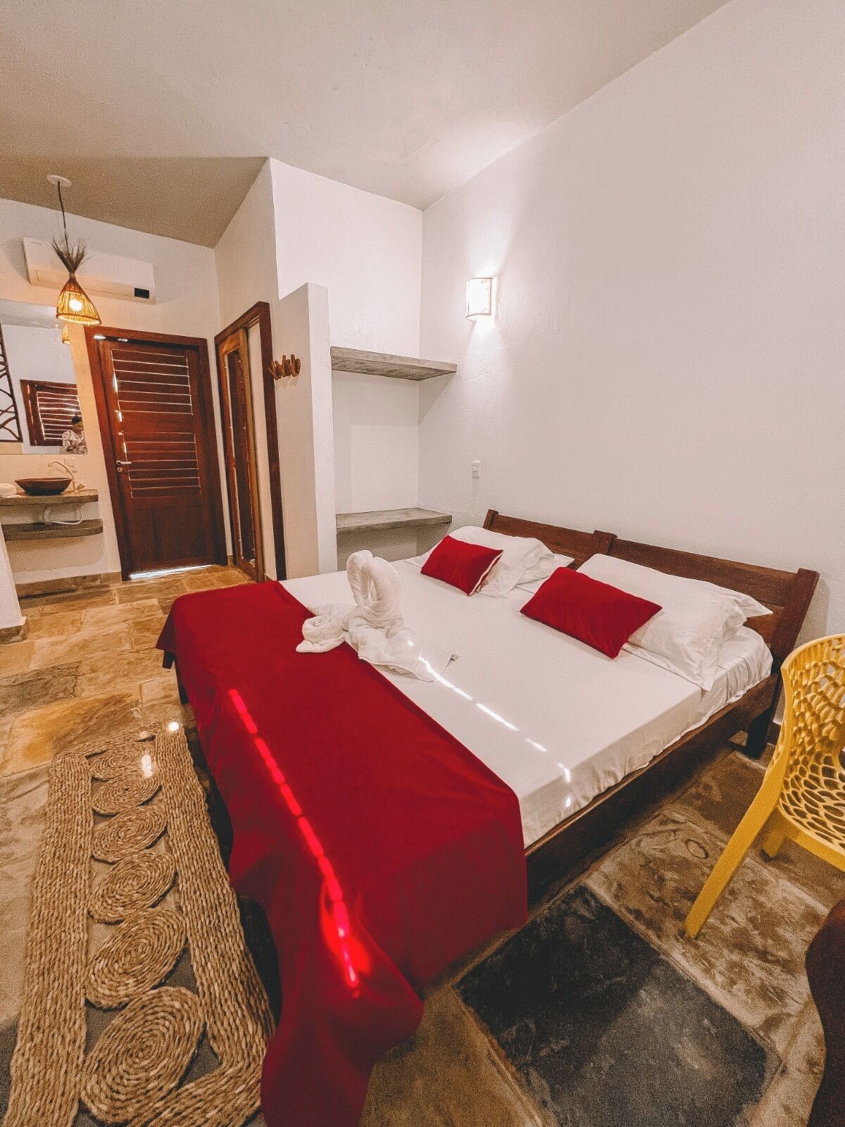 Ein Schlafzimmer mit einem Bett, einer Holztür, einem kleinen Regal und einem Stuhl.