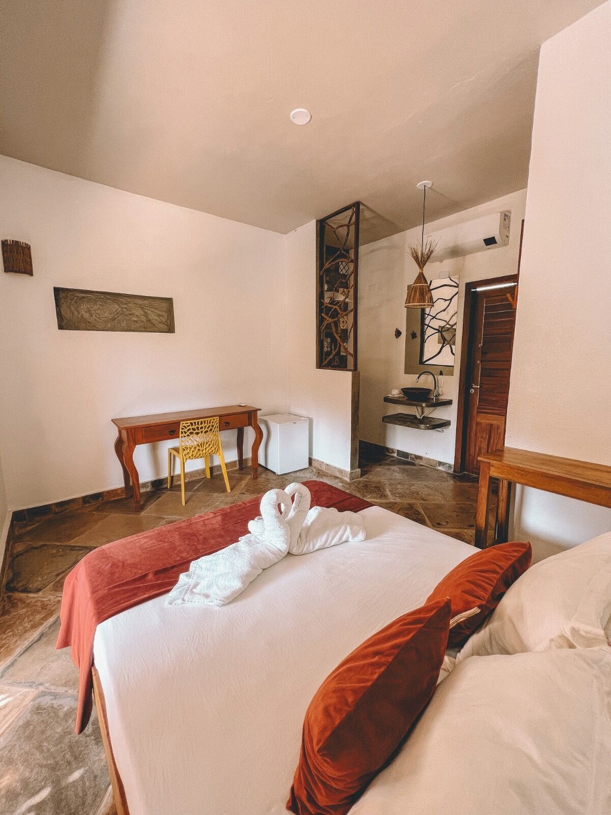 Una habitación de hotel con cama, escritorio, silla y una mesita.