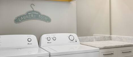 Een wasserette met twee witte Amana wasmachines en een bord erboven met de tekst '24 uur open Wasserette'.