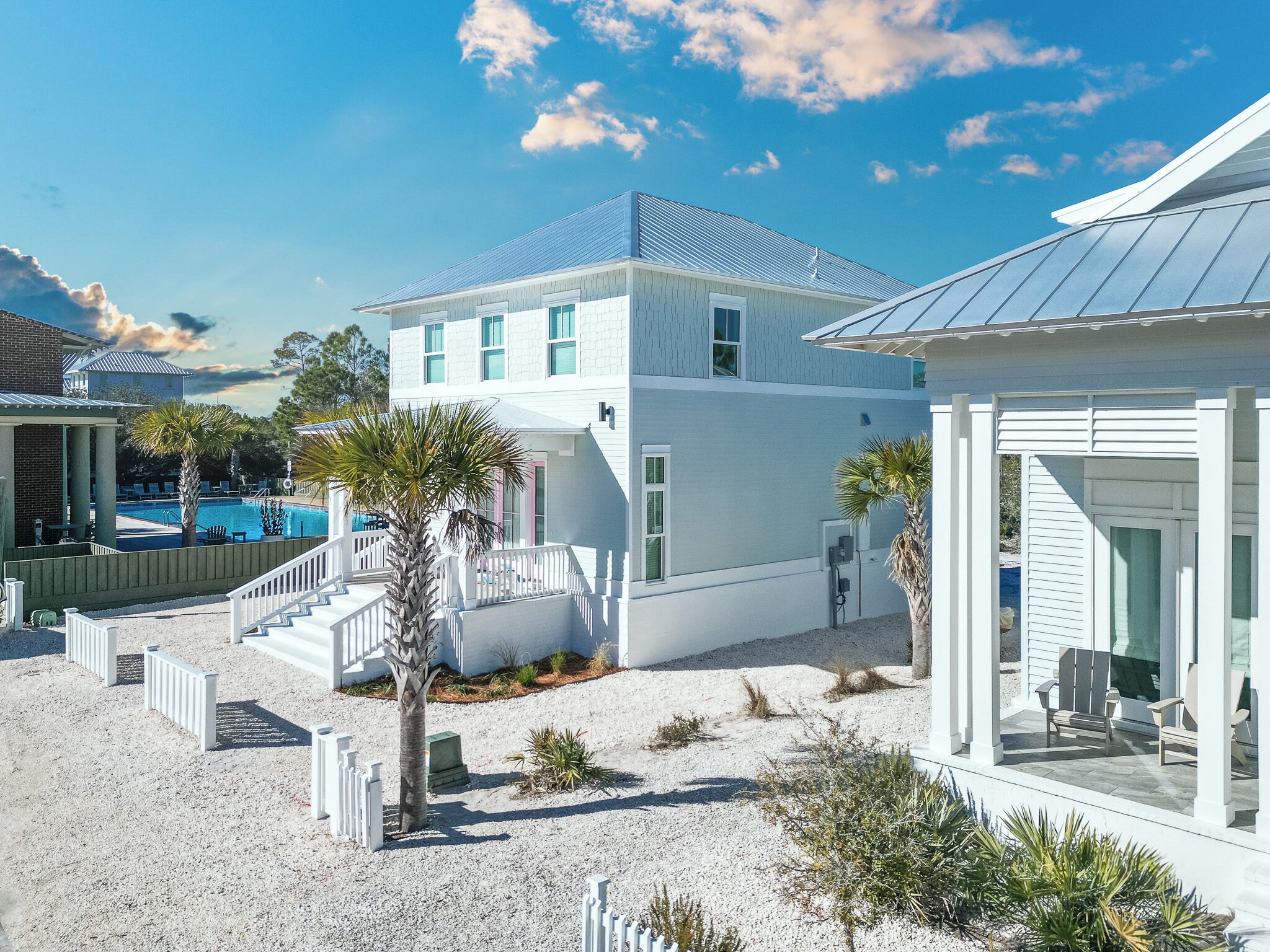 A white two-story house with a pool, white railings, and a covered patio area.