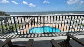 A balcony with a view of the ocean and a pool area.
