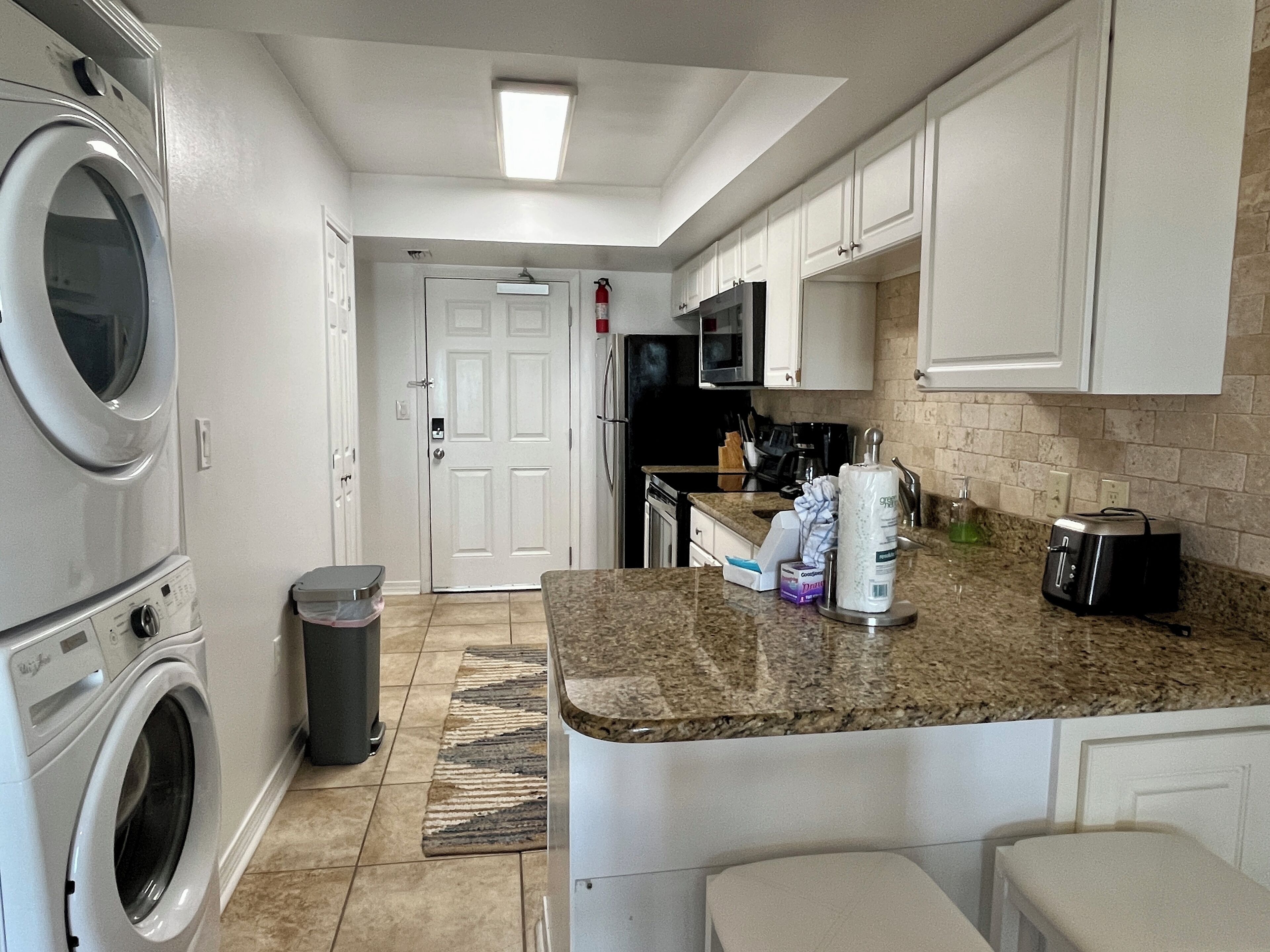 A compact kitchen with a built-in washer and dryer, a microwave, and a toaster.