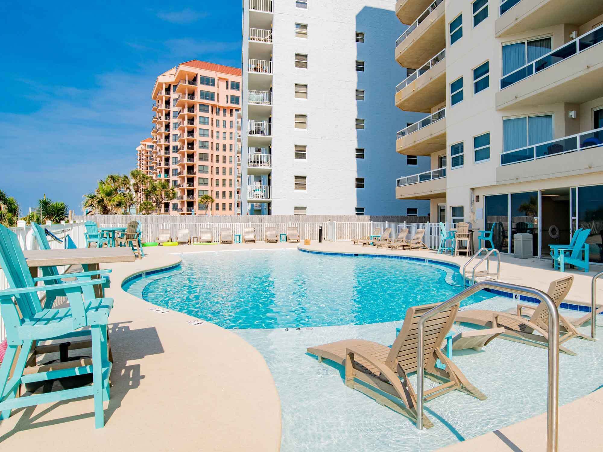 A pool area with lounge chairs and a view of high-rise buildings.