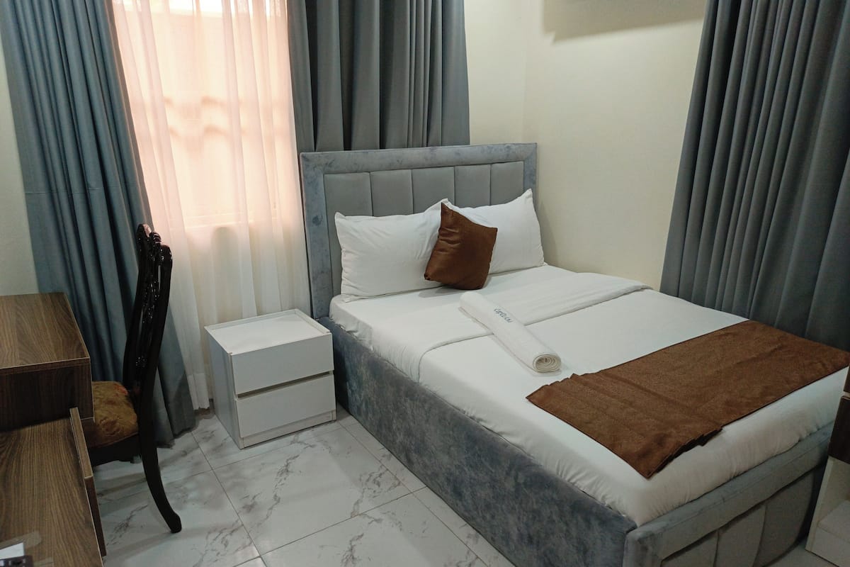 Une chambre d’hôtel avec un lit, une table de chevet, un bureau et une chaise.
