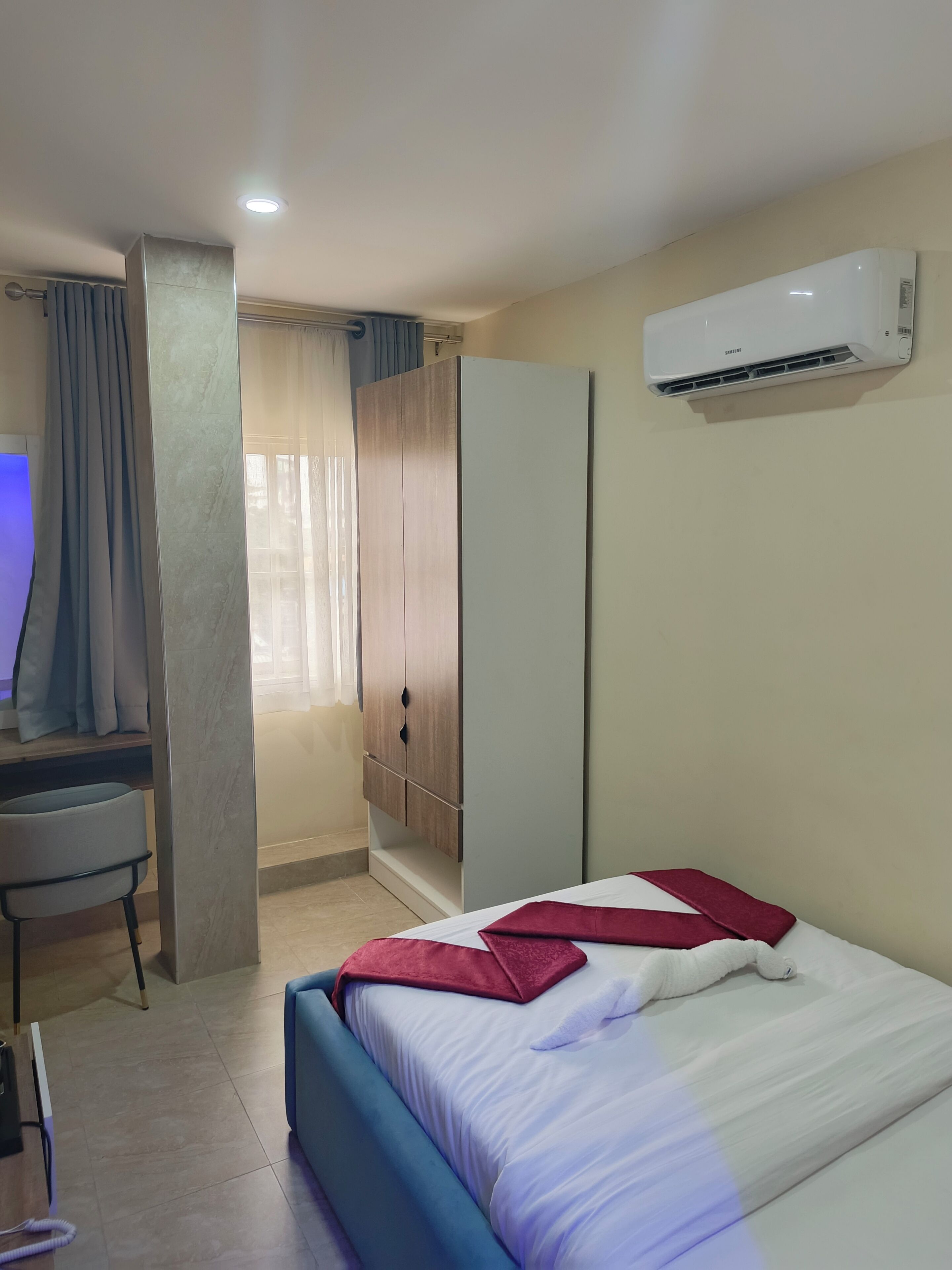 Een hotelkamer met een bed, een bureau, een kledingkast en een airconditioning.