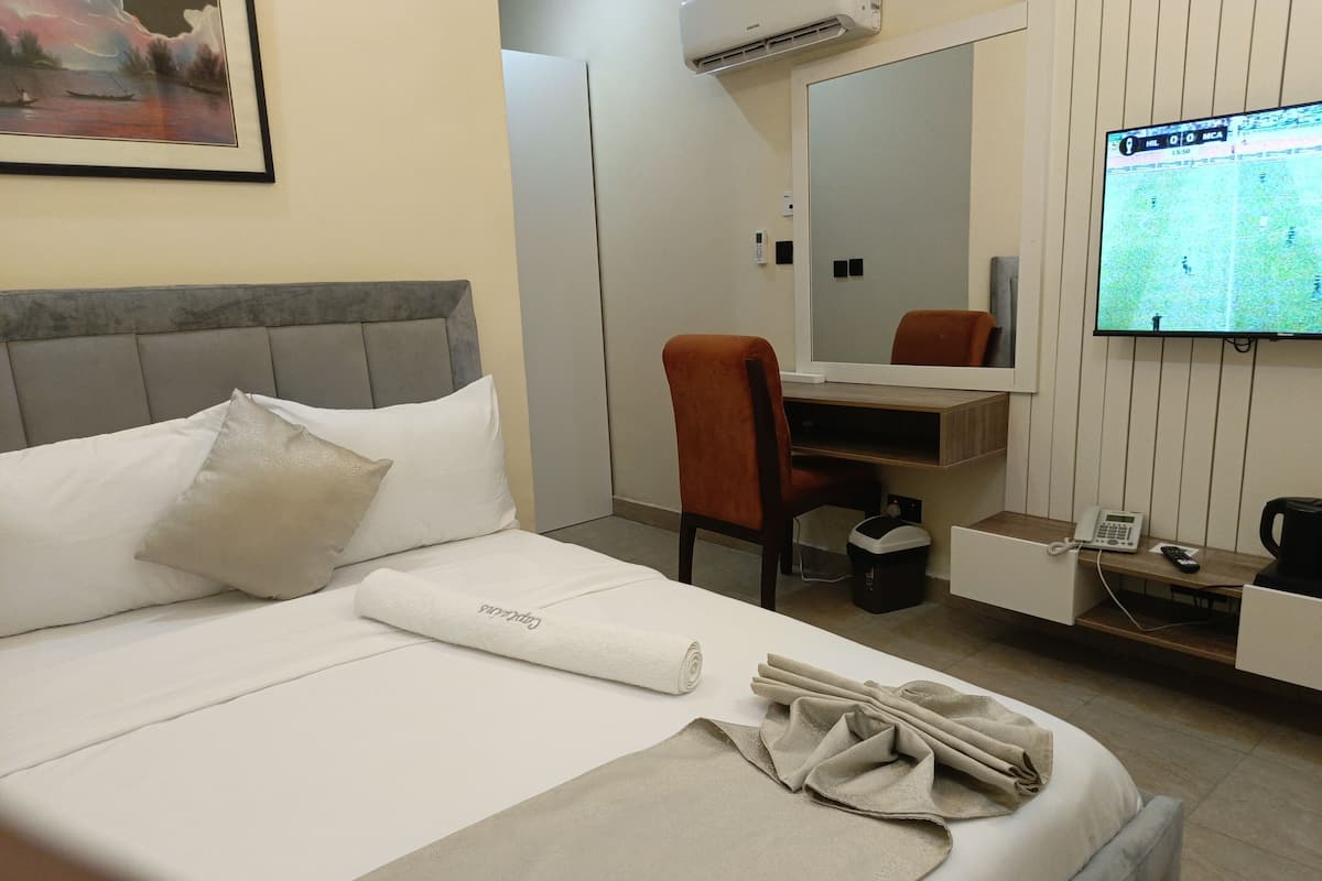 Une chambre d’hôtel équipée d’un lit, d’un bureau, d’une chaise, d’une télévision et d’un miroir.