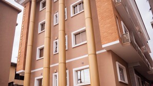 Un immeuble à plusieurs étages, doté d’une façade beige, de cadres de fenêtres blancs et d’une enseigne indiquant « Captain Residency Hotel ».