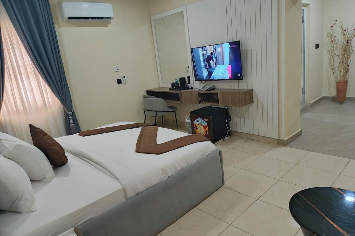 Une chambre d’hôtel équipée d’un lit, d’un bureau, d’une télévision et d’un réfrigérateur de la marque Nexus.