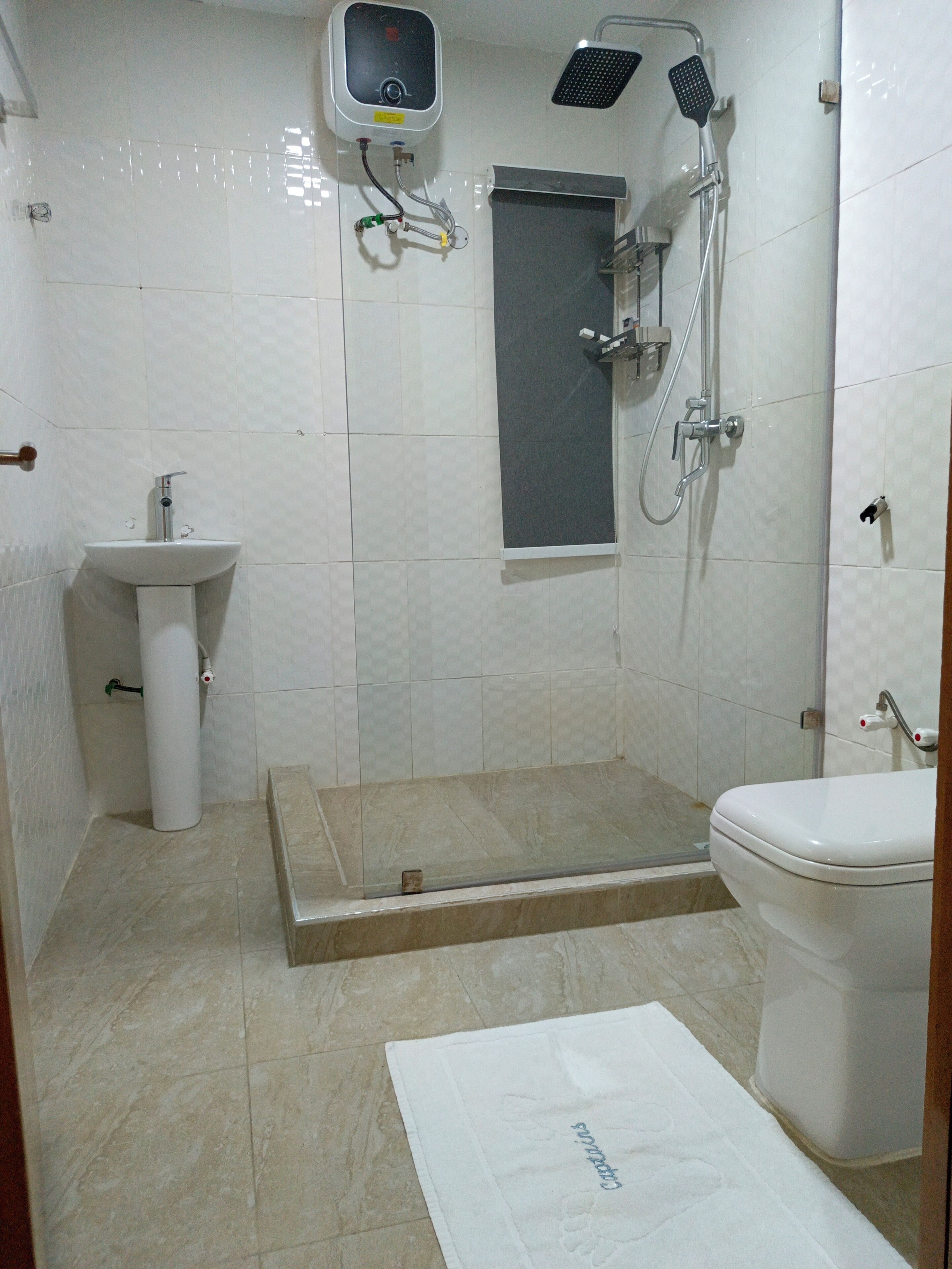 Une salle de bain comprenant des toilettes, un lavabo, une douche et un espace de douche fermé par des parois en verre.