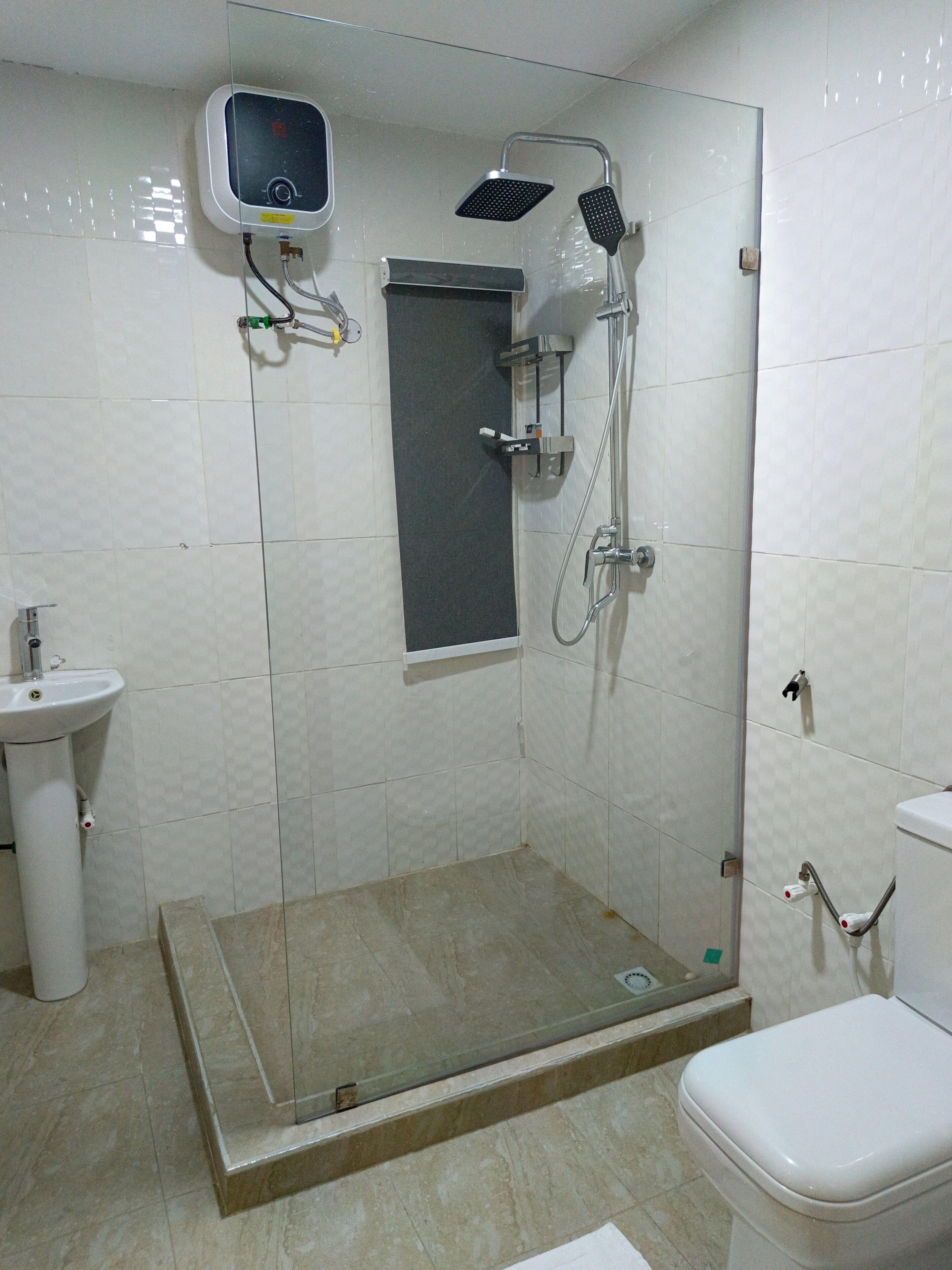 A bathroom with a glass-enclosed shower, a sink, and a toilet.
