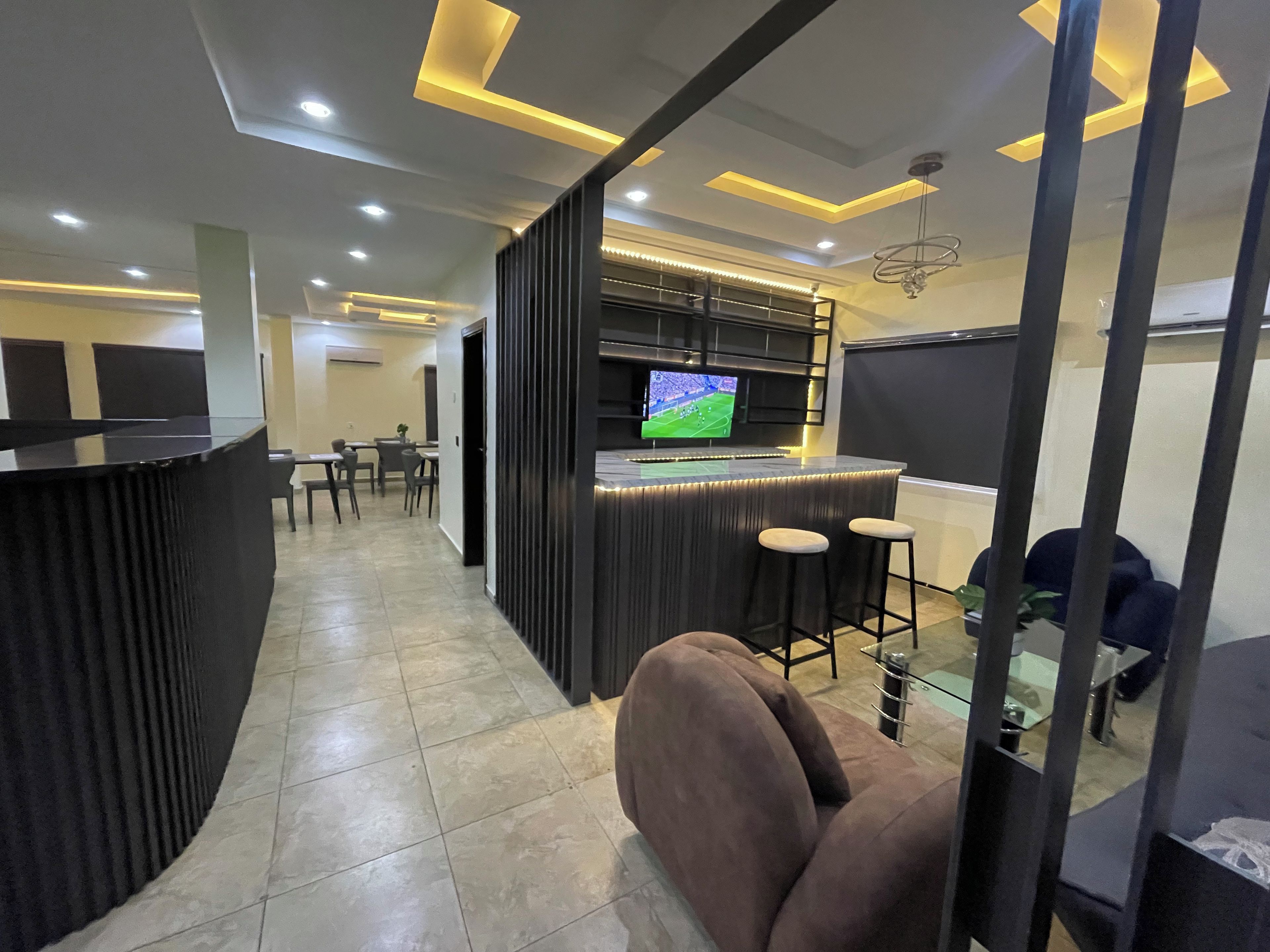 A modern bar area with a television, seating, and a counter.