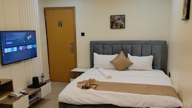 Une chambre d’hôtel moderne équipée d’un grand lit, d’une télévision, d’un bureau avec un téléphone et d’un canapé.