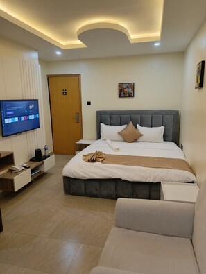A modern hotel room with a large bed, a TV, a desk with a phone, and a couch. - Captain Residency Hotel (Lagos)